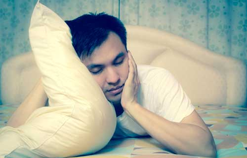 Man clutching pillow not able to sleep